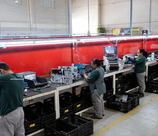 Equipe desmontando e descaracterizando impressoras em bancadas