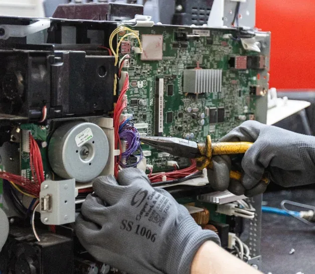 Técnico separando componentes eletrônicos de uma impressora para reciclagem