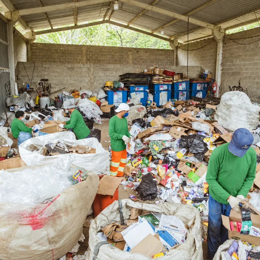 Trabalhadores separando materiais recicláveis em um galpão de triagem